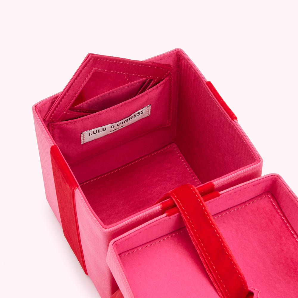 Open pink Lulu Guinness box with red velvet accents and interior compartments.