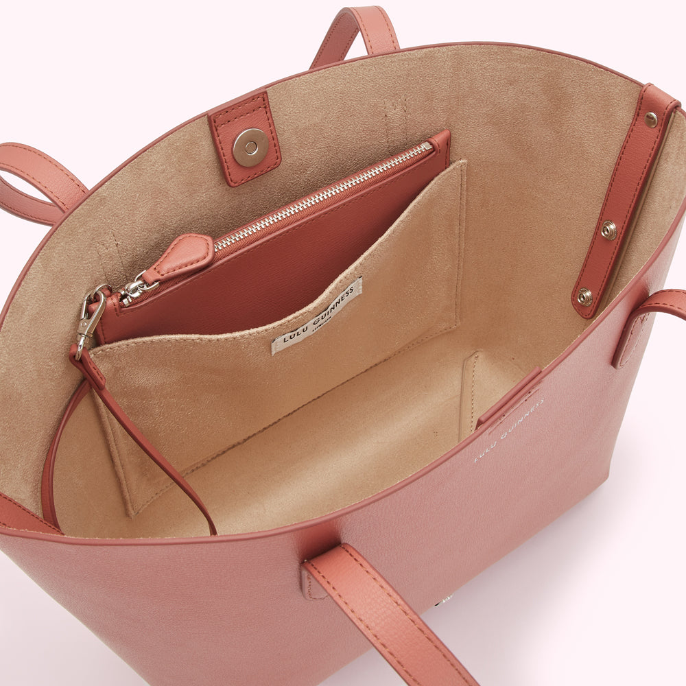 Interior of a dusty rose Lulu Guinness tote bag showing beige lining, zippered pocket, and brand label.
