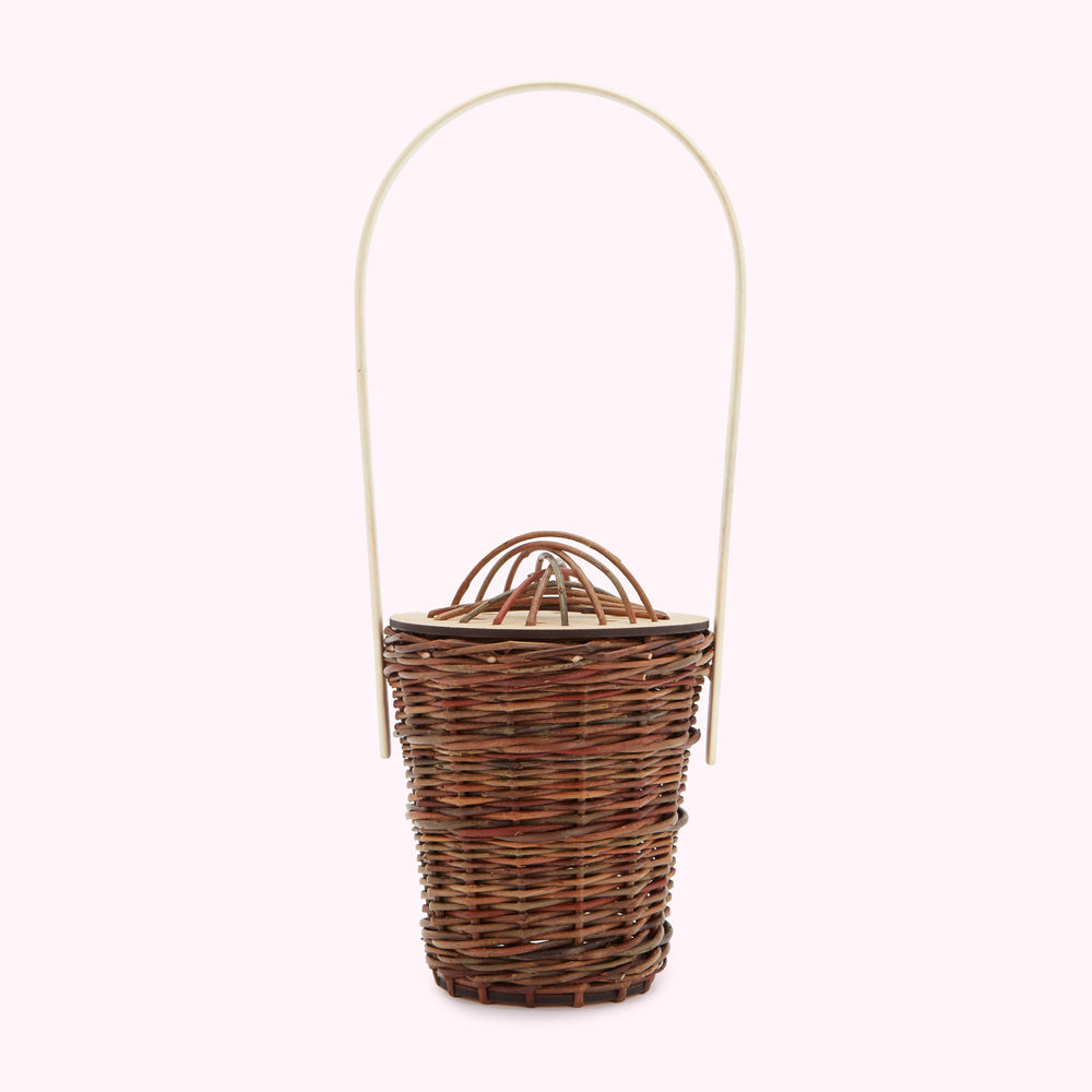 A brown wicker basket with a cream-colored handle against a white background.