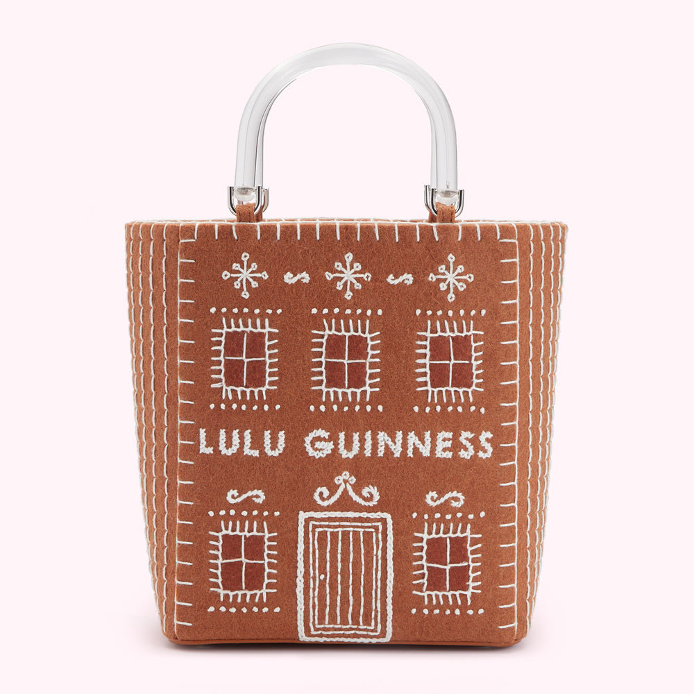 Brown felt tote bag shaped like a gingerbread house with clear acrylic handles, embroidered with "Lulu Guinness".