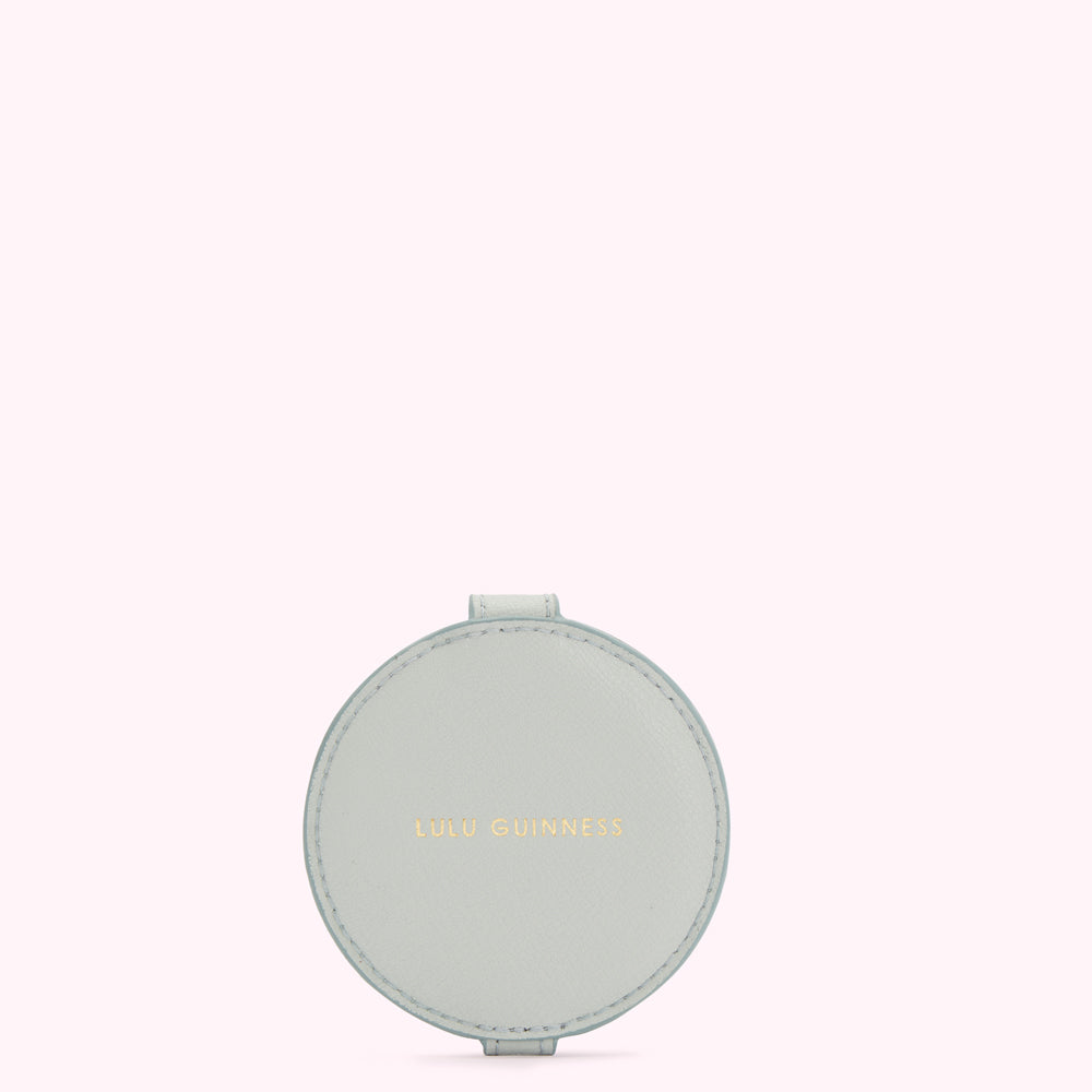 Light blue circular compact mirror with the text "Lulu Guinness" embossed in gold.
