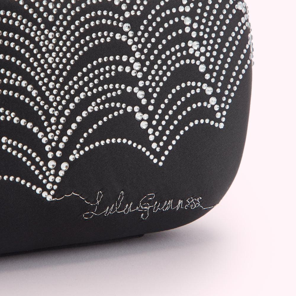 Close-up of a black Lulu Guinness clutch adorned with a silver, sparkly, firework-like design.
