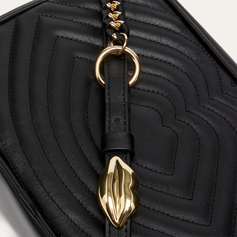 Black quilted handbag with a gold lip-shaped buckle and strap on a light gray background