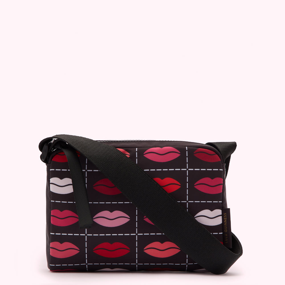 Black crossbody bag with a grid pattern of lips in various shades of red and pink on a black background.