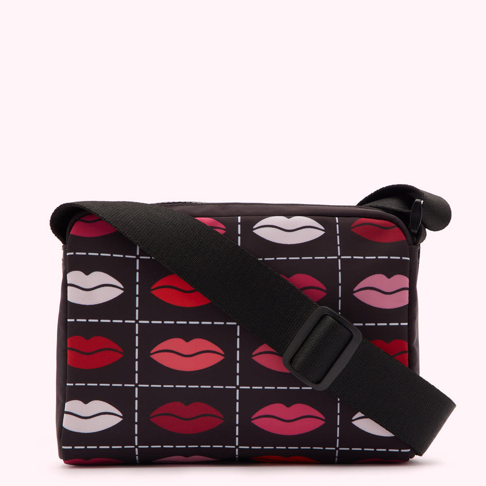 Black crossbody bag with a pattern of lips in various shades of red and pink on a white background.