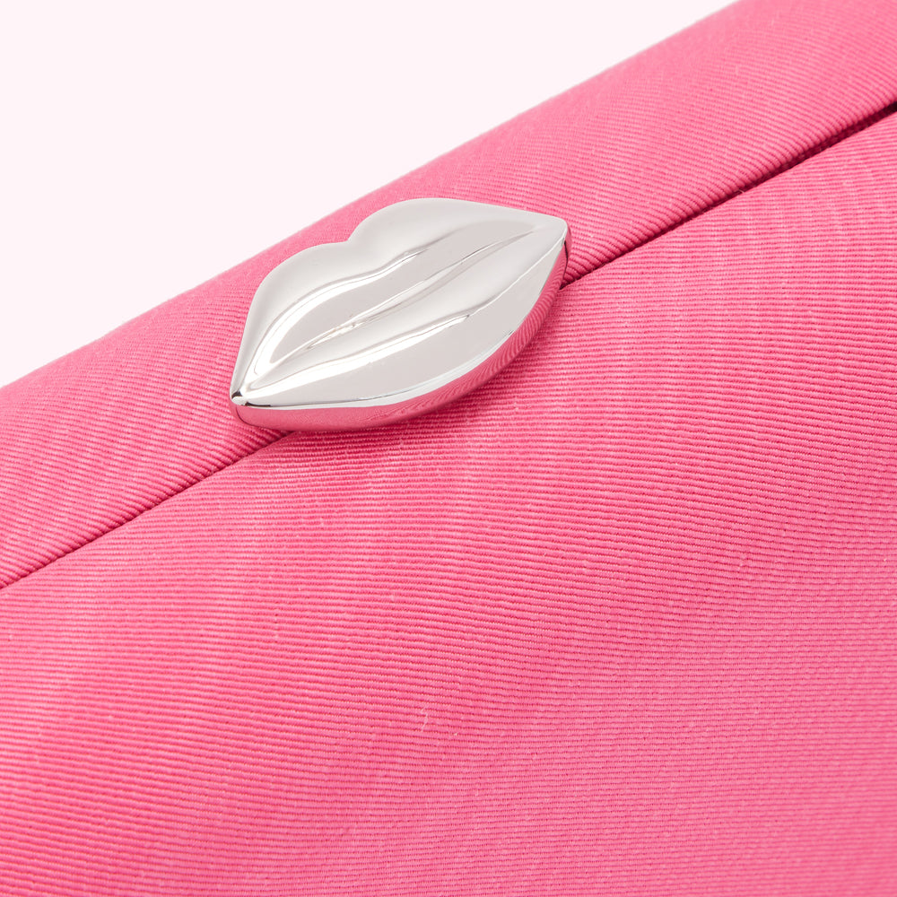 Close-up of a pink clutch with a silver lip-shaped clasp.
