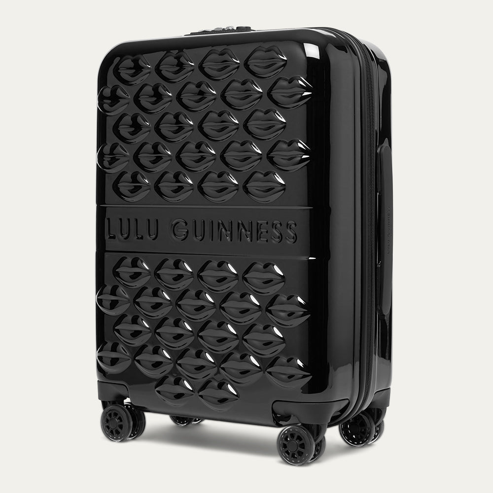 Black suitcase with Lulu Guinness branding on a light gray background