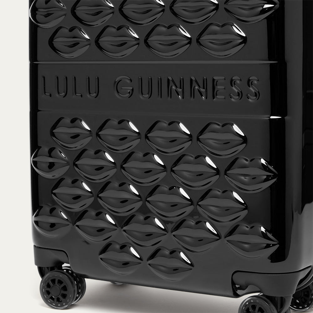 Black suitcase with lips pattern and 'Lulu Guinness' branding