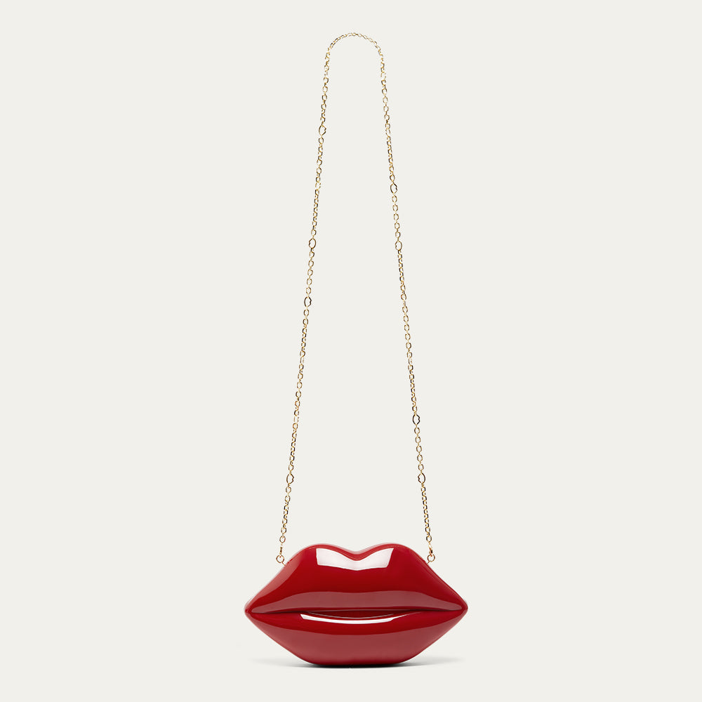 Red lip-shaped handbag with a gold chain on a light beige background