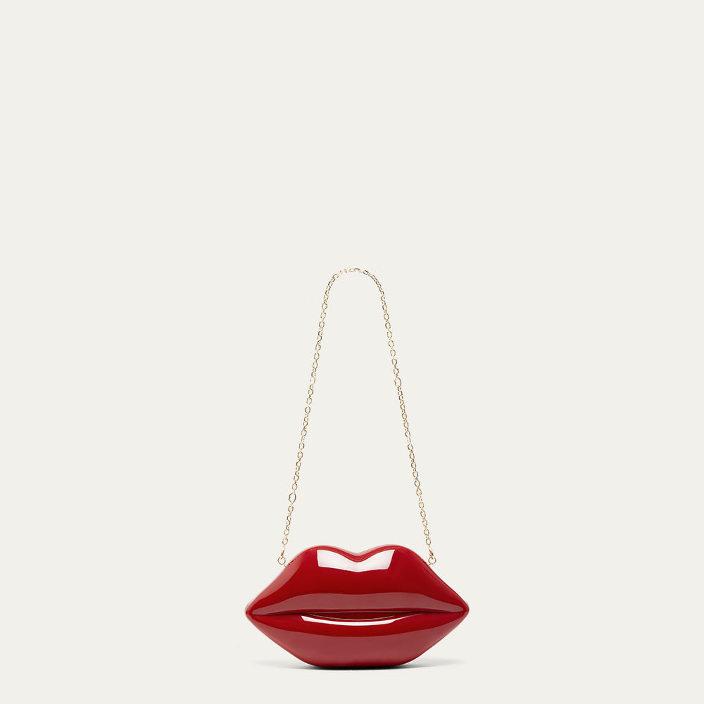 Red lip-shaped handbag with a gold chain on a light beige background