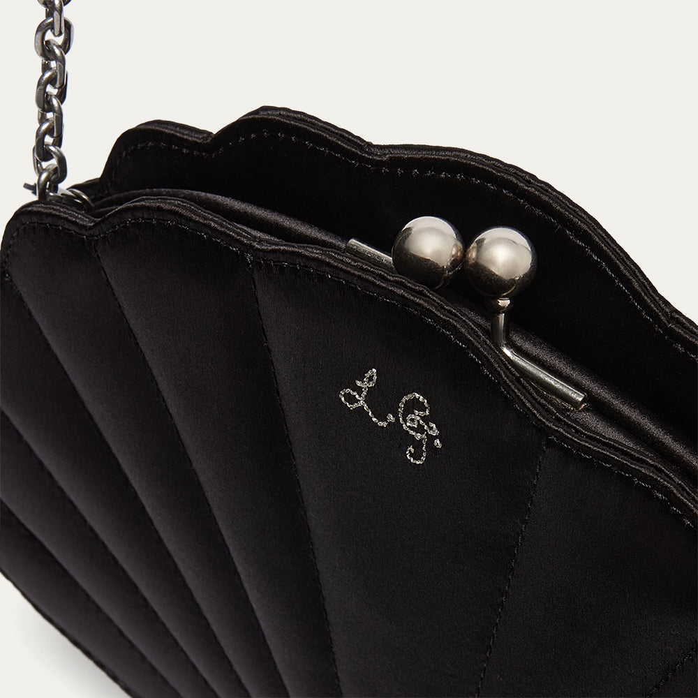 Black handbag with pearl embellishments and a visible brand logo on a white background