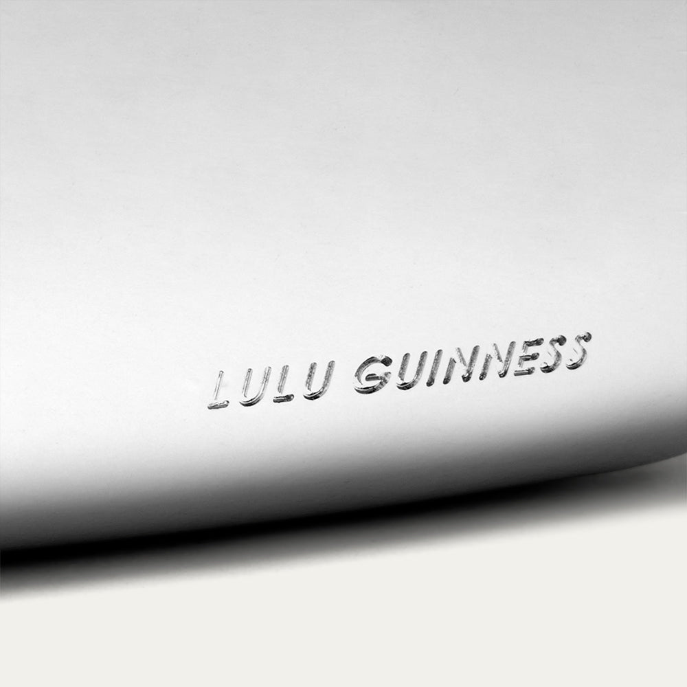 Lulu Guinness logo embossed on a silver lip-shaped clutch.