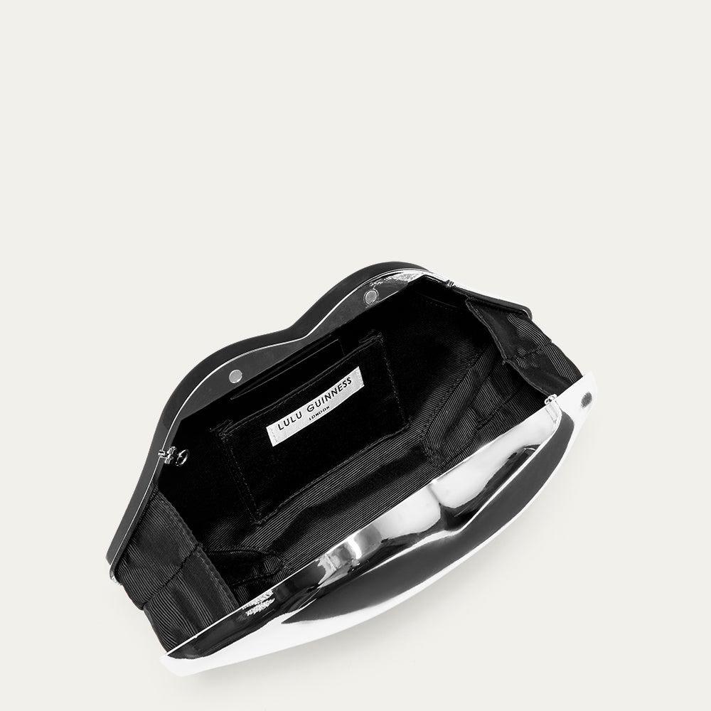 Silver lip-shaped clutch bag open to reveal a black lining and 'Lulu Guinness' branded label on a light grey background.