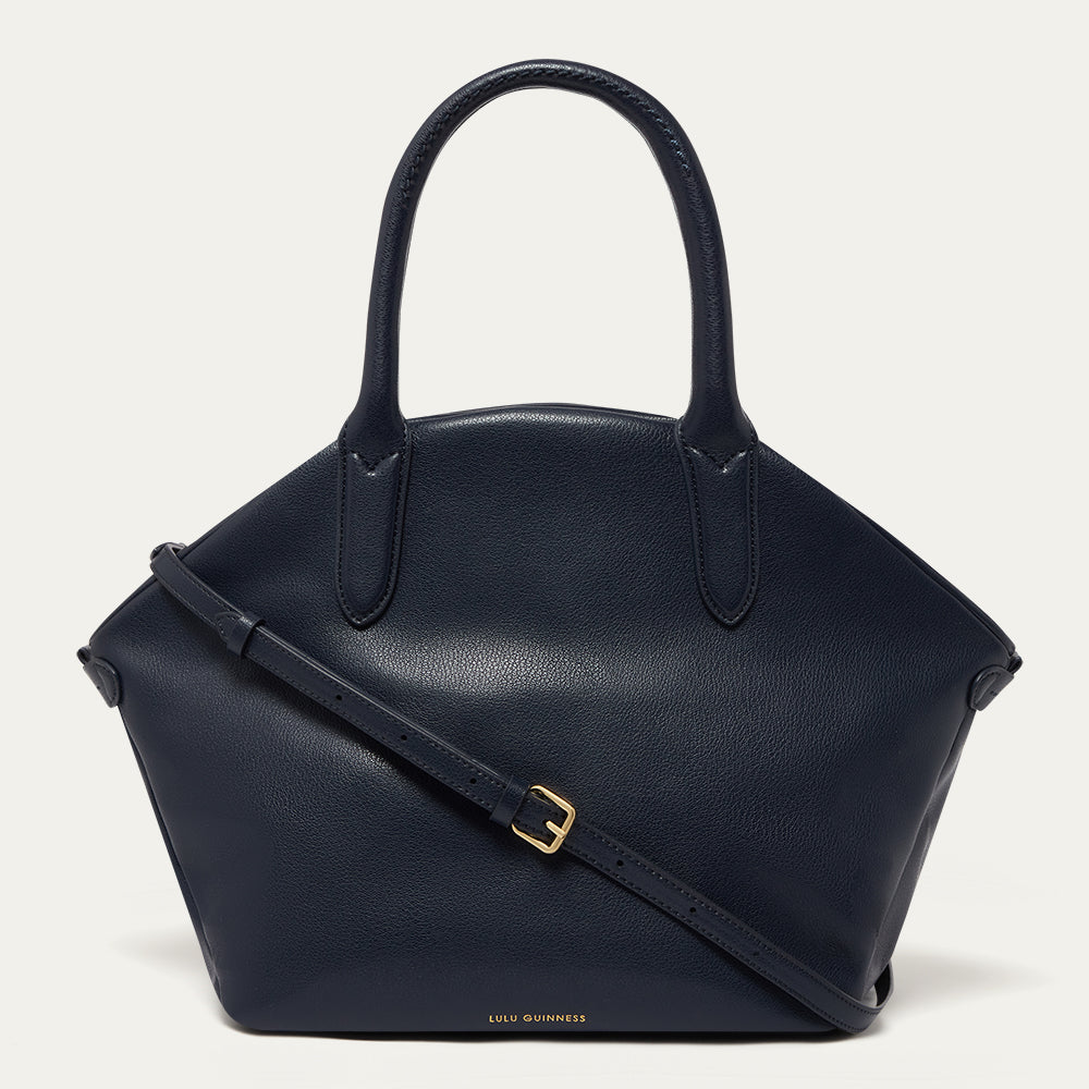 Navy blue leather tote bag with a gold buckle on a light gray background