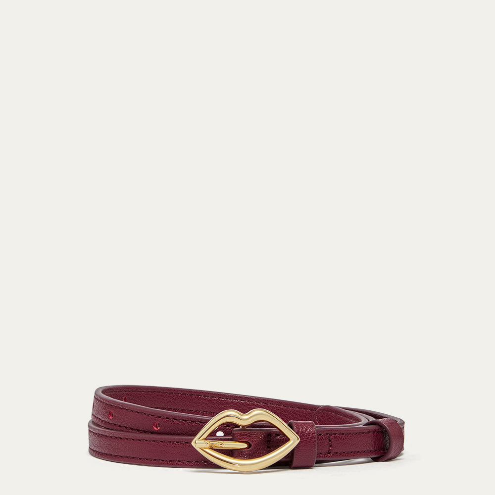 Burgundy belt with a gold lip shaped buckle on a light grey background