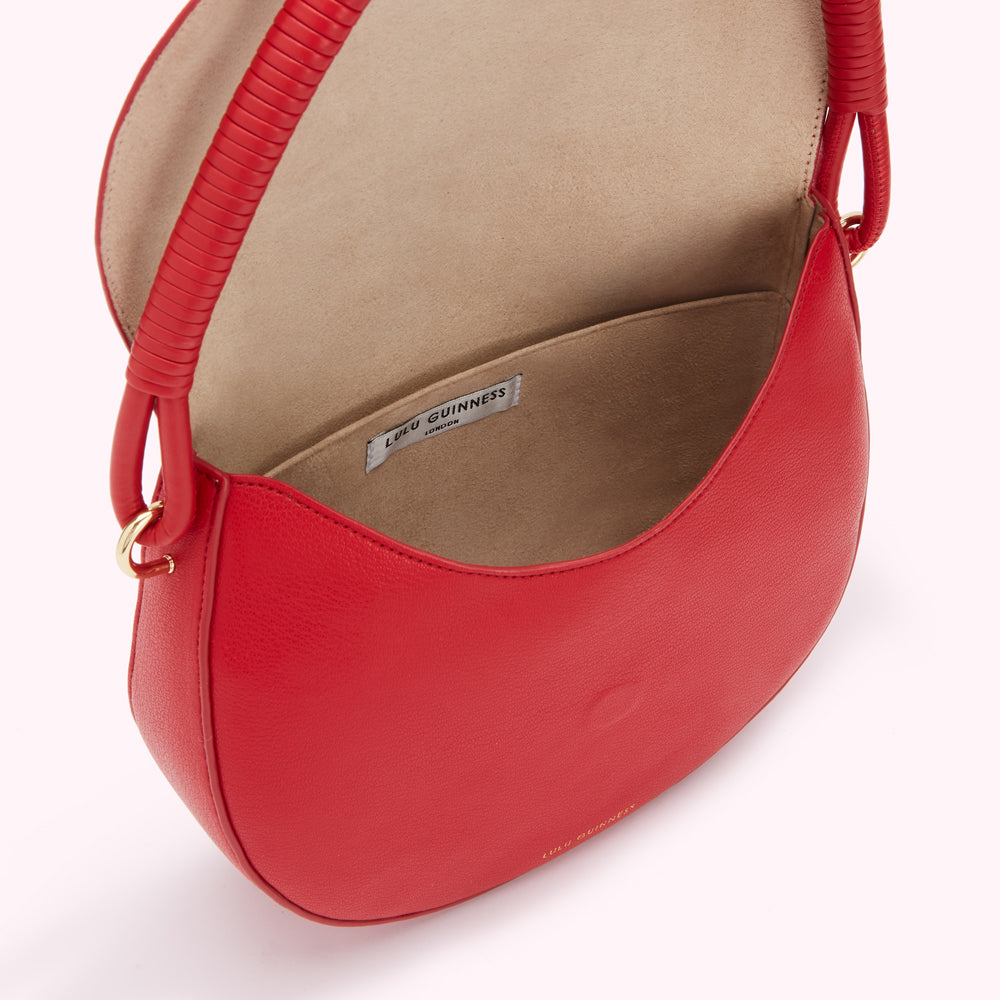Inside view of a red Lulu Guinness London handbag with a beige interior and a twisted leather handle.