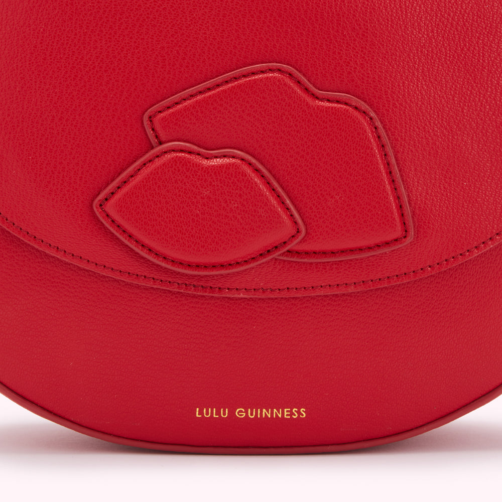 Close-up of a red Lulu Guinness handbag with a lip design.
