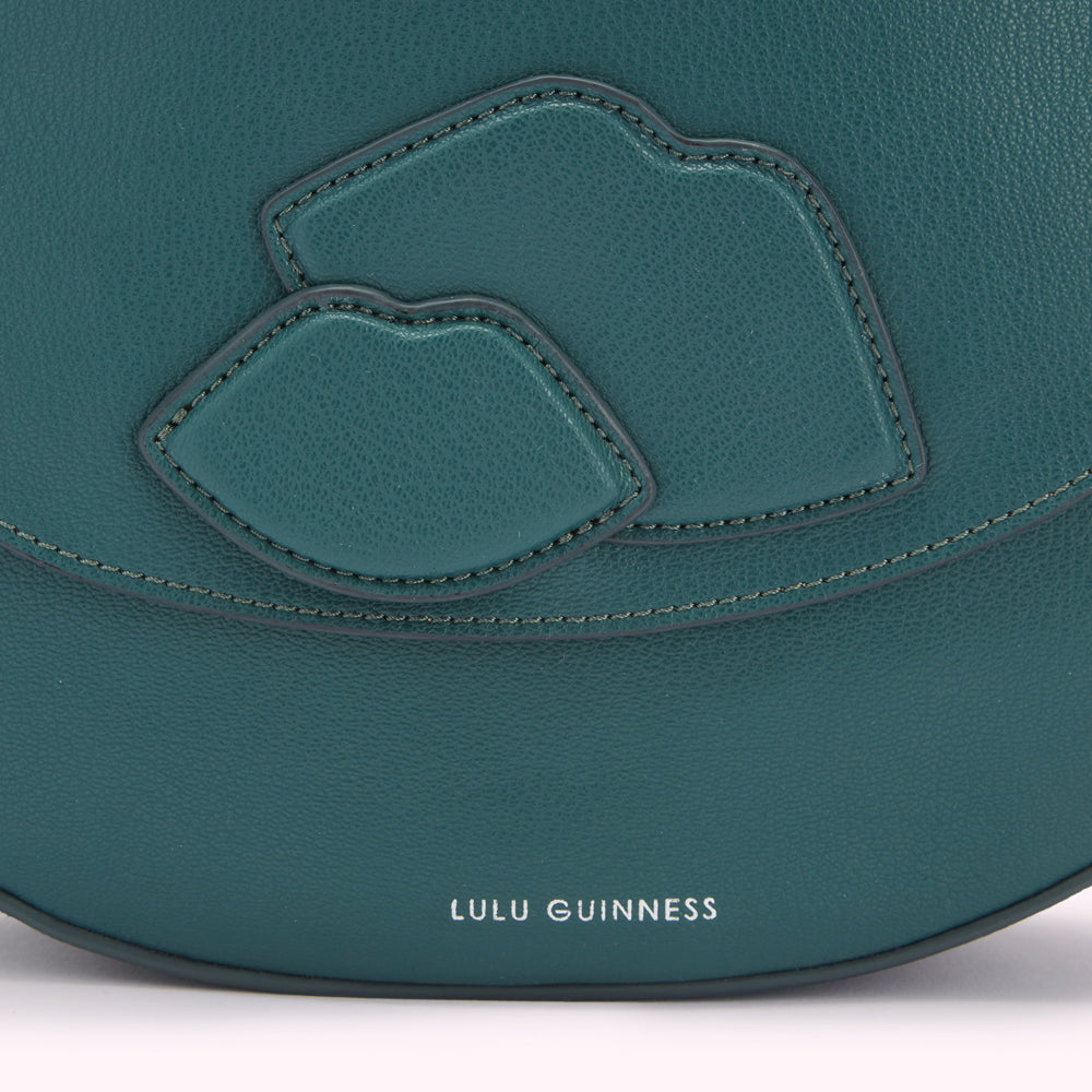 Close-up of a teal Lulu Guinness handbag featuring two lips design.
