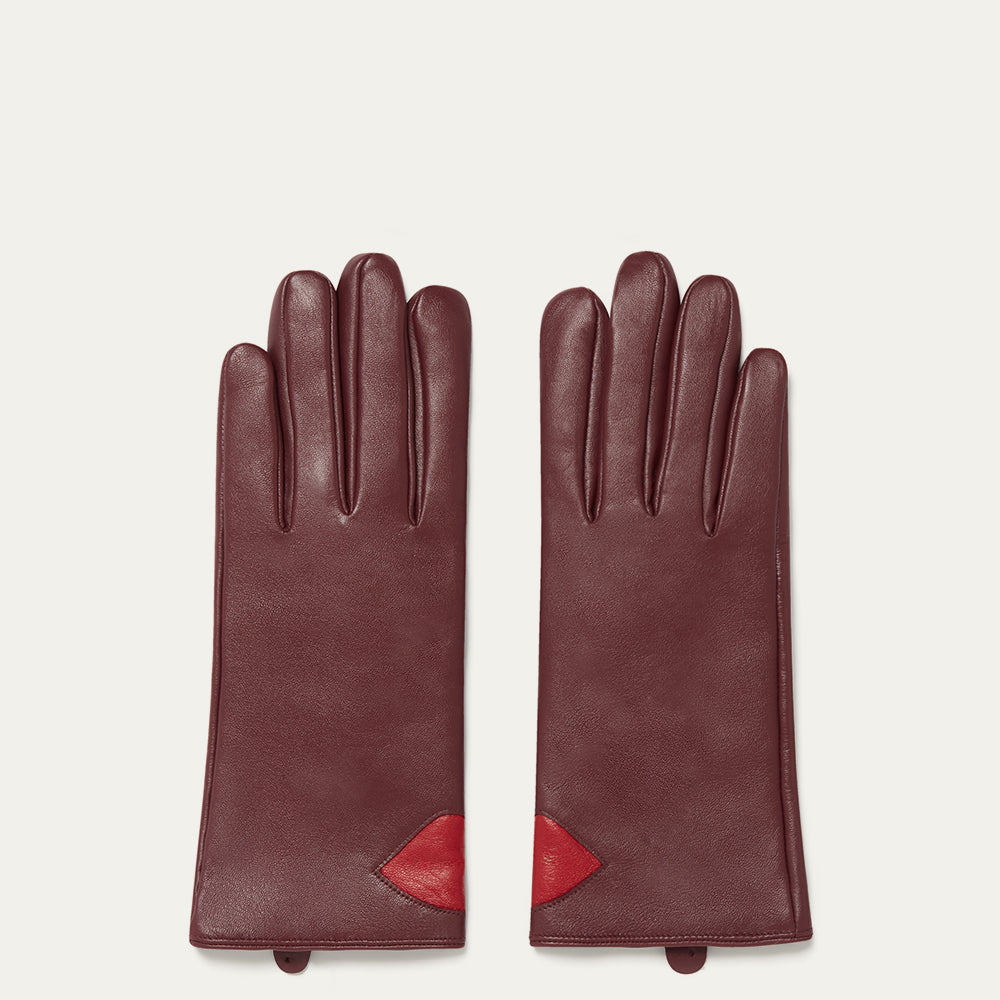 Pair of burgundy leather gloves with red accents on a light beige background