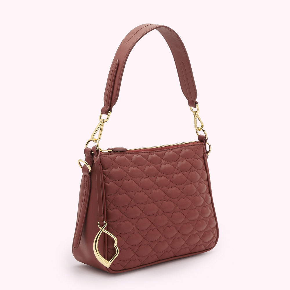 A russet quilted handbag with a gold lip-shaped charm.
