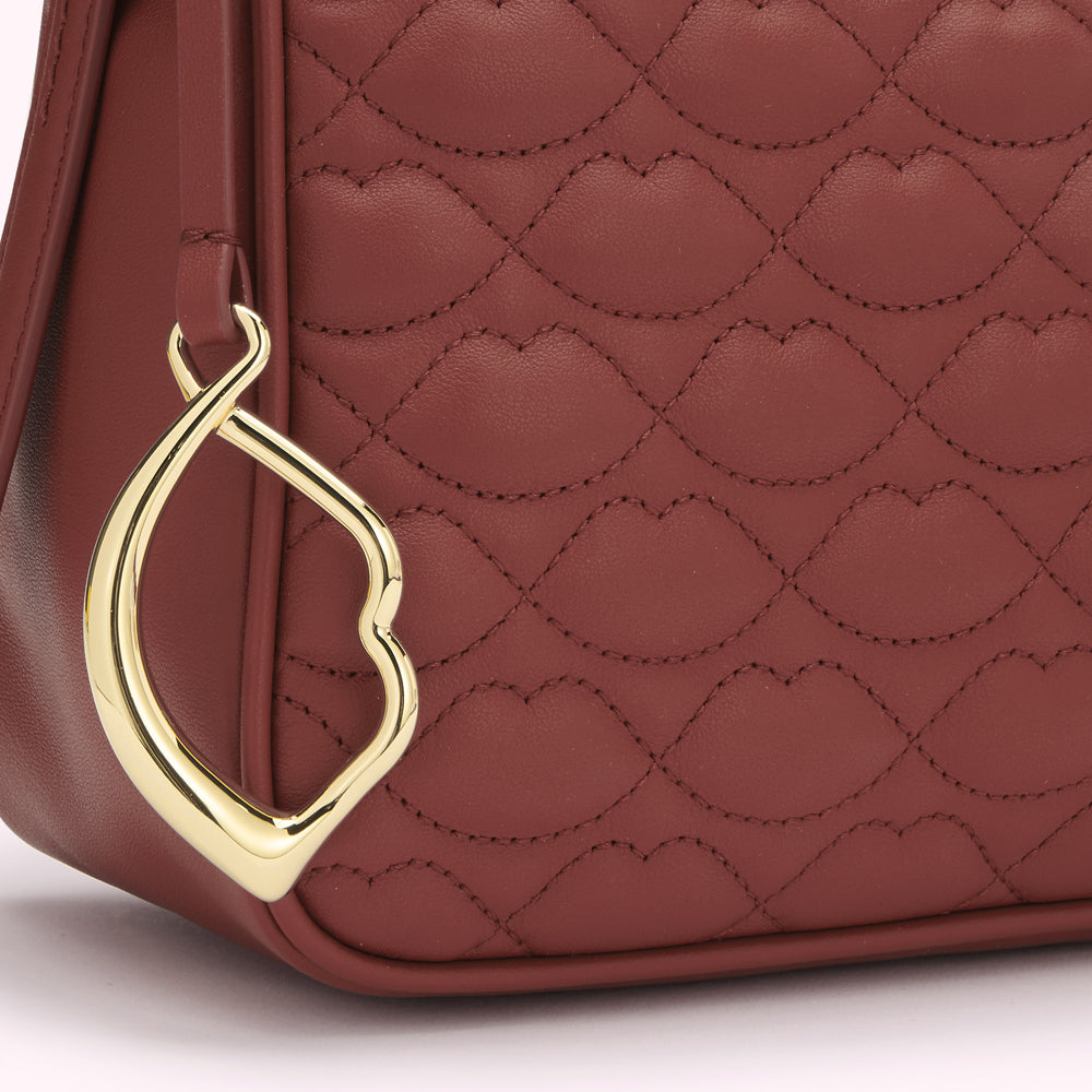 Close-up of a russet quilted handbag with a gold heart-shaped detail.