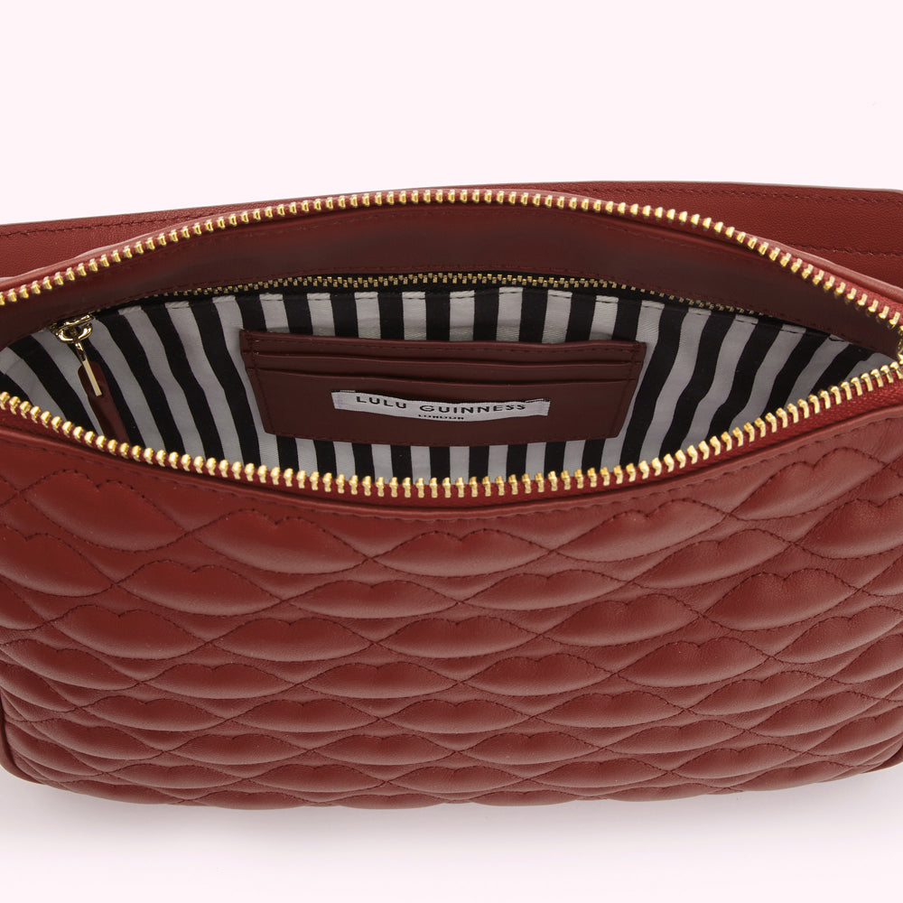Inside of a russet quilted Lulu Guinness purse with a black and white striped lining.