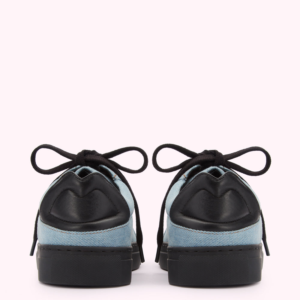 Pair of light blue denim sneakers with black laces and black leather accents on a white background.