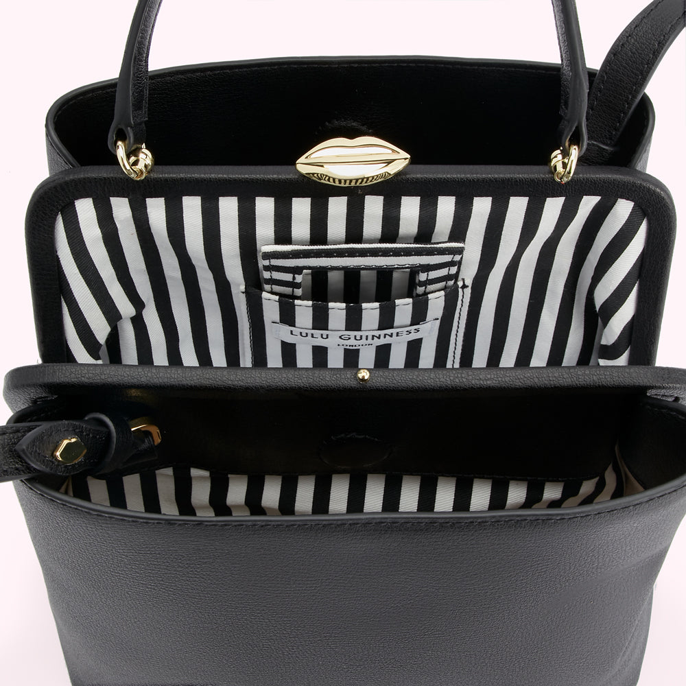 Open black Lulu Guinness handbag with gold lips clasp and black and white striped interior.