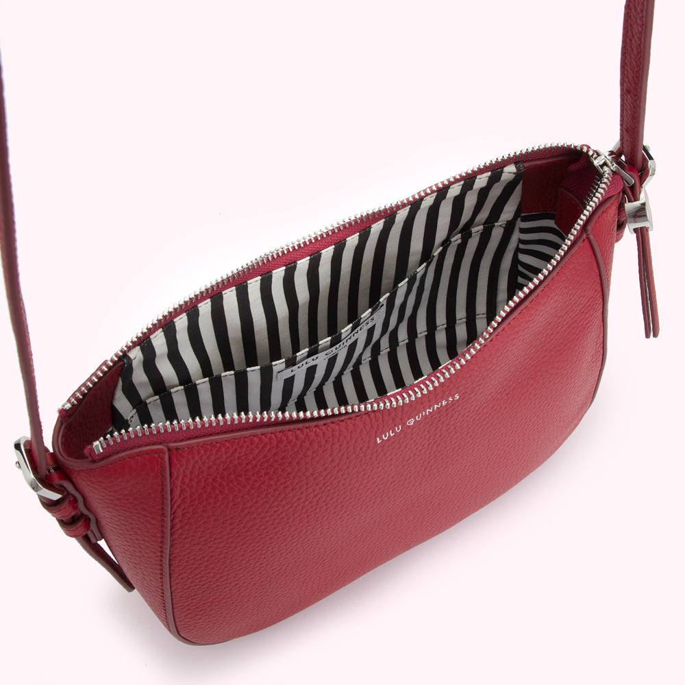 Red Lulu Guinness crossbody bag with black and white striped interior.
