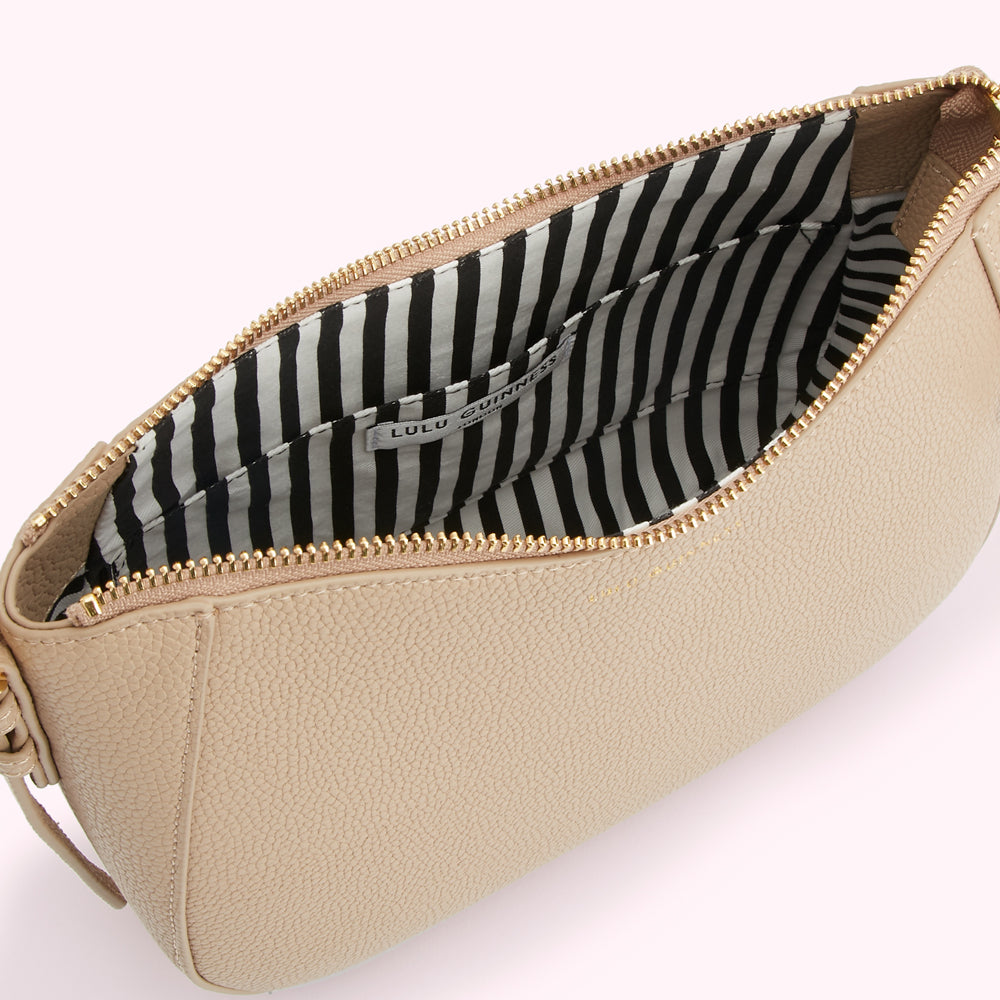 Beige Lulu Guinness crossbody bag open to reveal a black and white striped interior.
