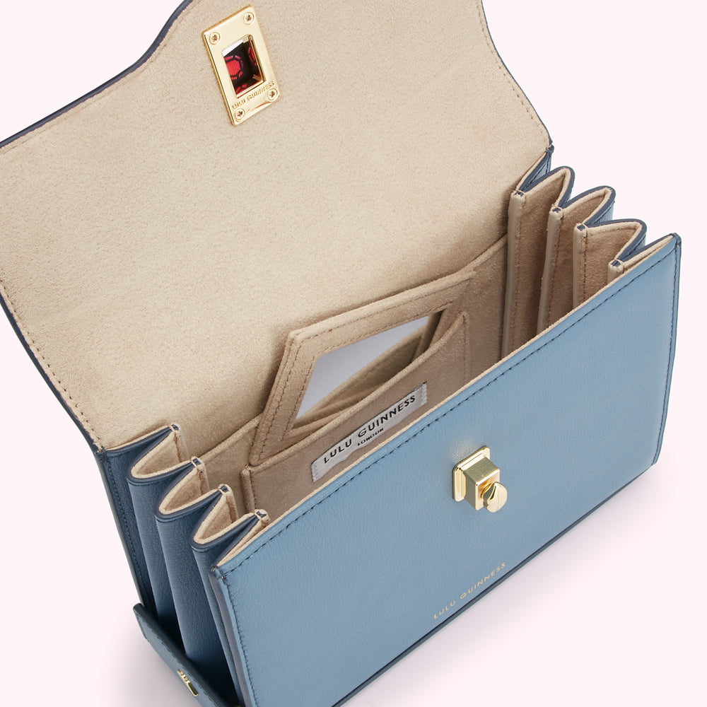 Open blue Lulu Guinness handbag showing beige interior with multiple compartments and gold hardware.