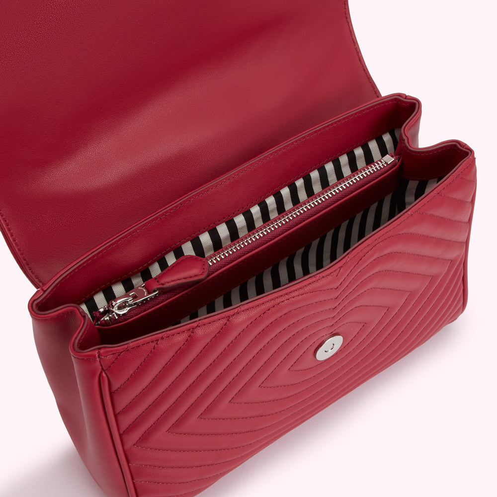 Red quilted leather handbag open to reveal its black and white striped interior and zipper.
