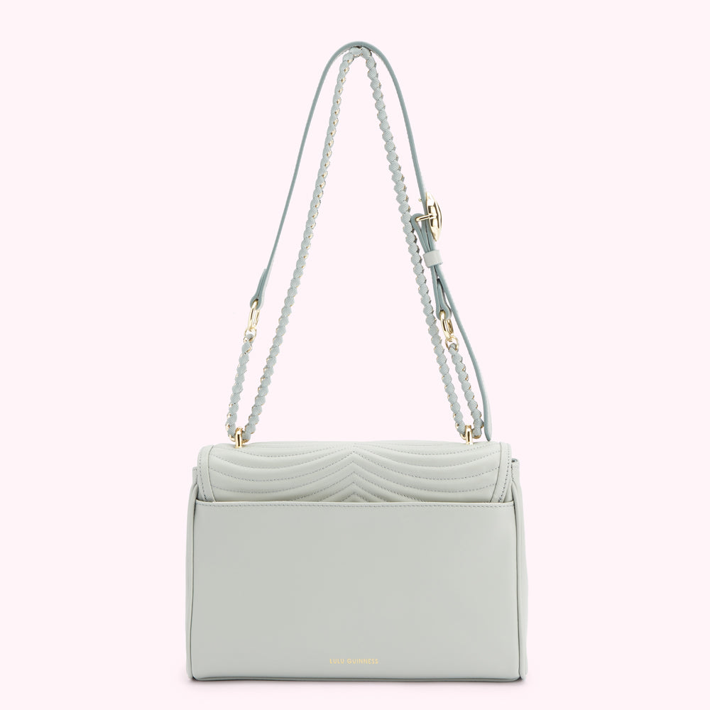 Back view of a light teal quilted shoulder bag with braided gold straps and gold clasp. The brand name "Lulu Guinness" is subtly printed on the back.
