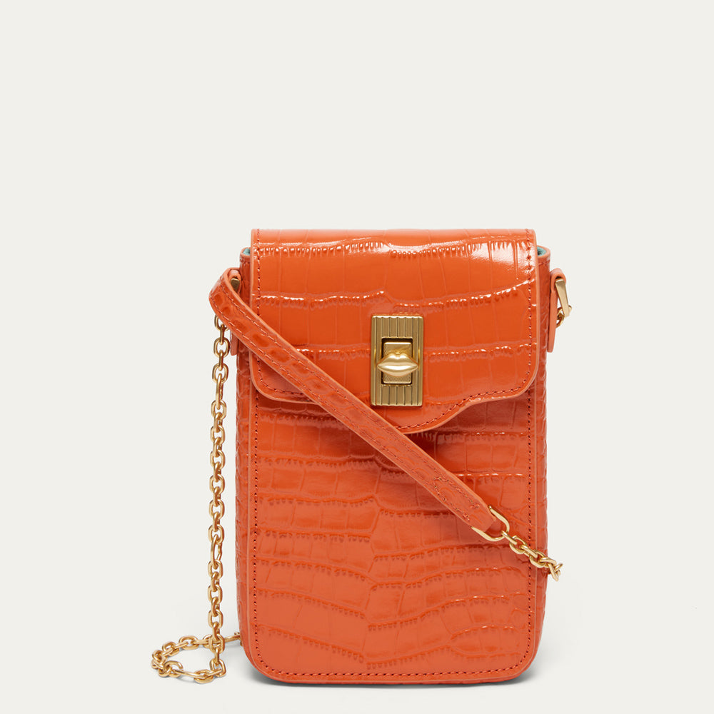 An orange croc affect embossed leather crossbody phone bag with a gold-tone turn-lock clasp and a gold chain strap, shown against a light off-white background.
