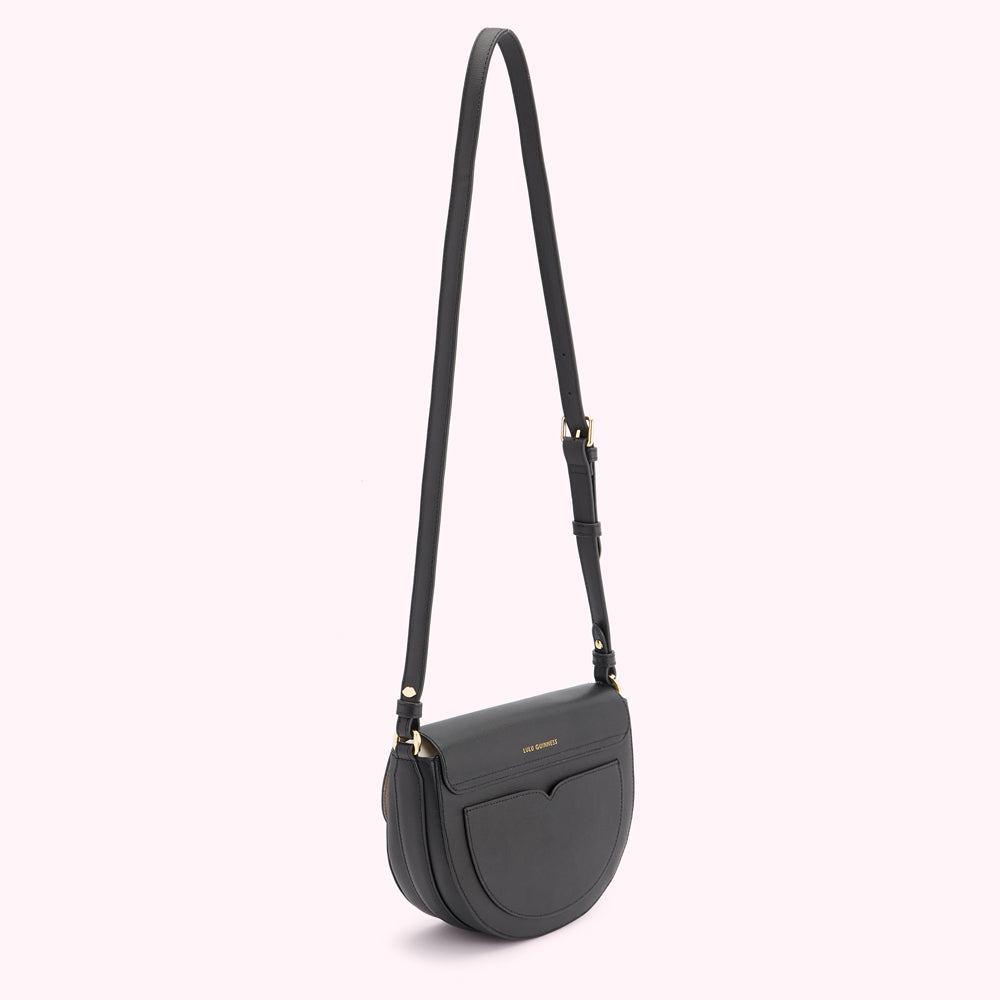 Black half-moon crossbody bag with gold hardware against a white background.
