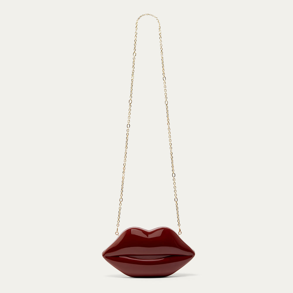 Lip-shaped handbag with a gold chain on a light beige background