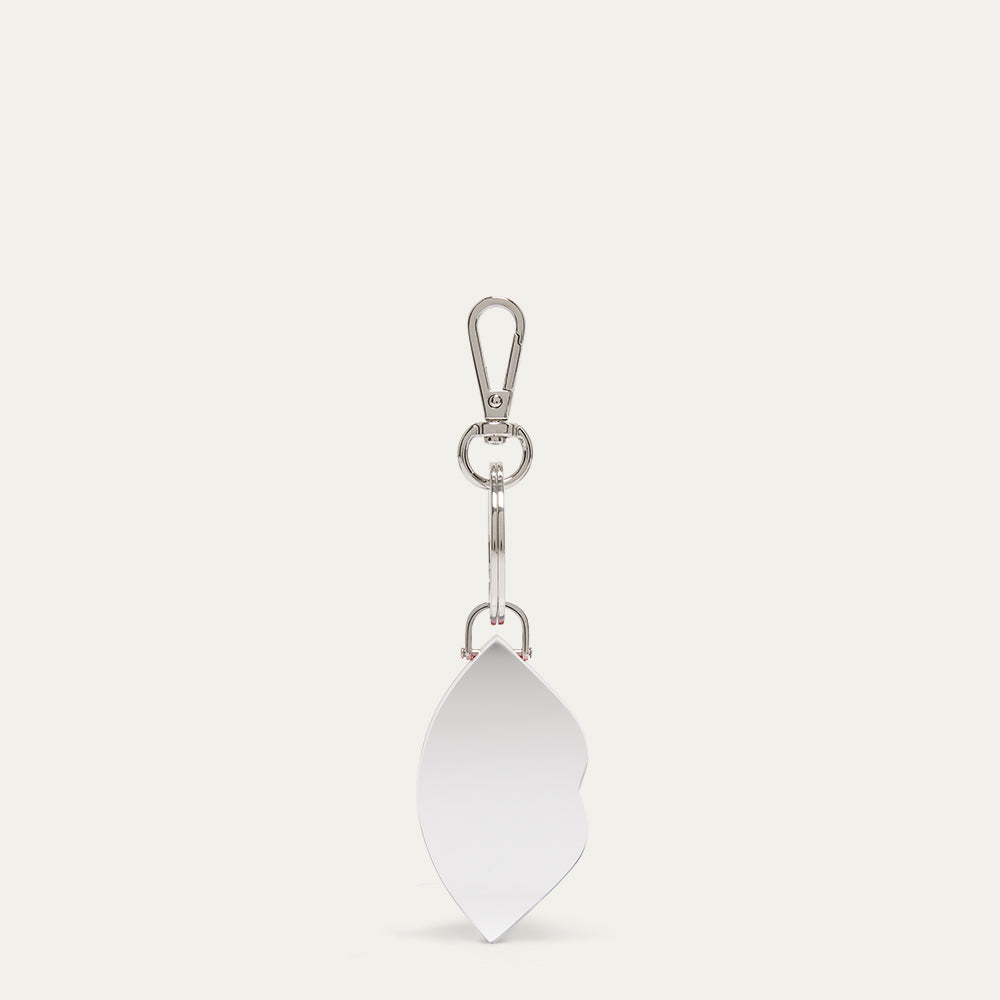 A silver-toned metal keychain featuring a flat, lip-shaped charm, attached to a lobster clasp and rings, shown on a light off-white background.