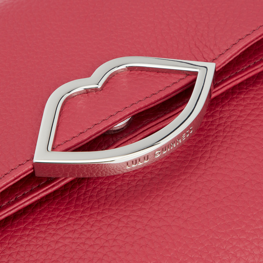 Close-up of a red Lulu Guinness purse with a silver lip-shaped clasp.
