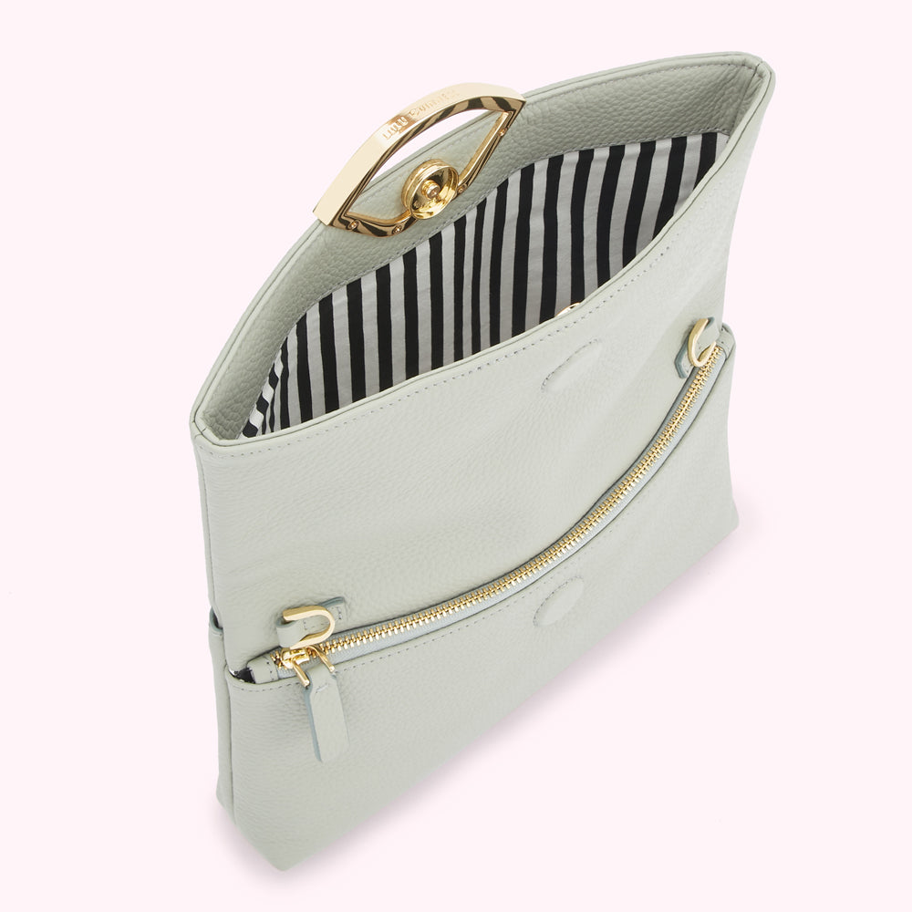 Pale grey leather crossbody bag with gold hardware and black and white striped interior.
