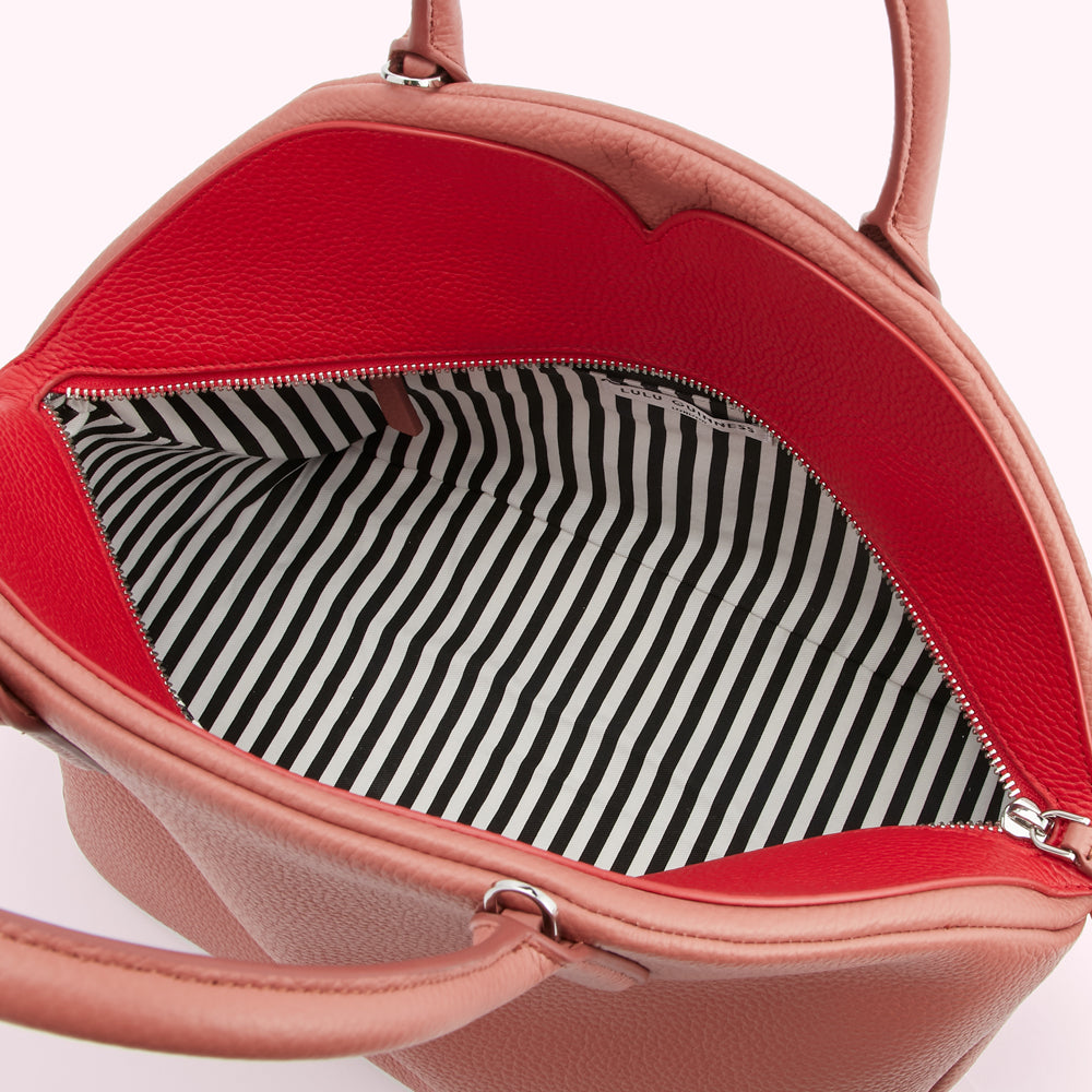 Dusty rose Lulu Guinness handbag open to reveal a red interior and black and white striped lining.