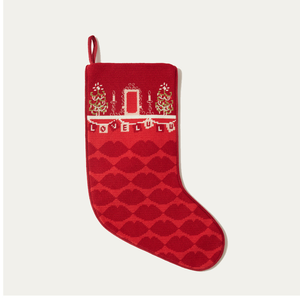 Red Christmas stocking with a needle point 'Love Lulu' pattern on a white background