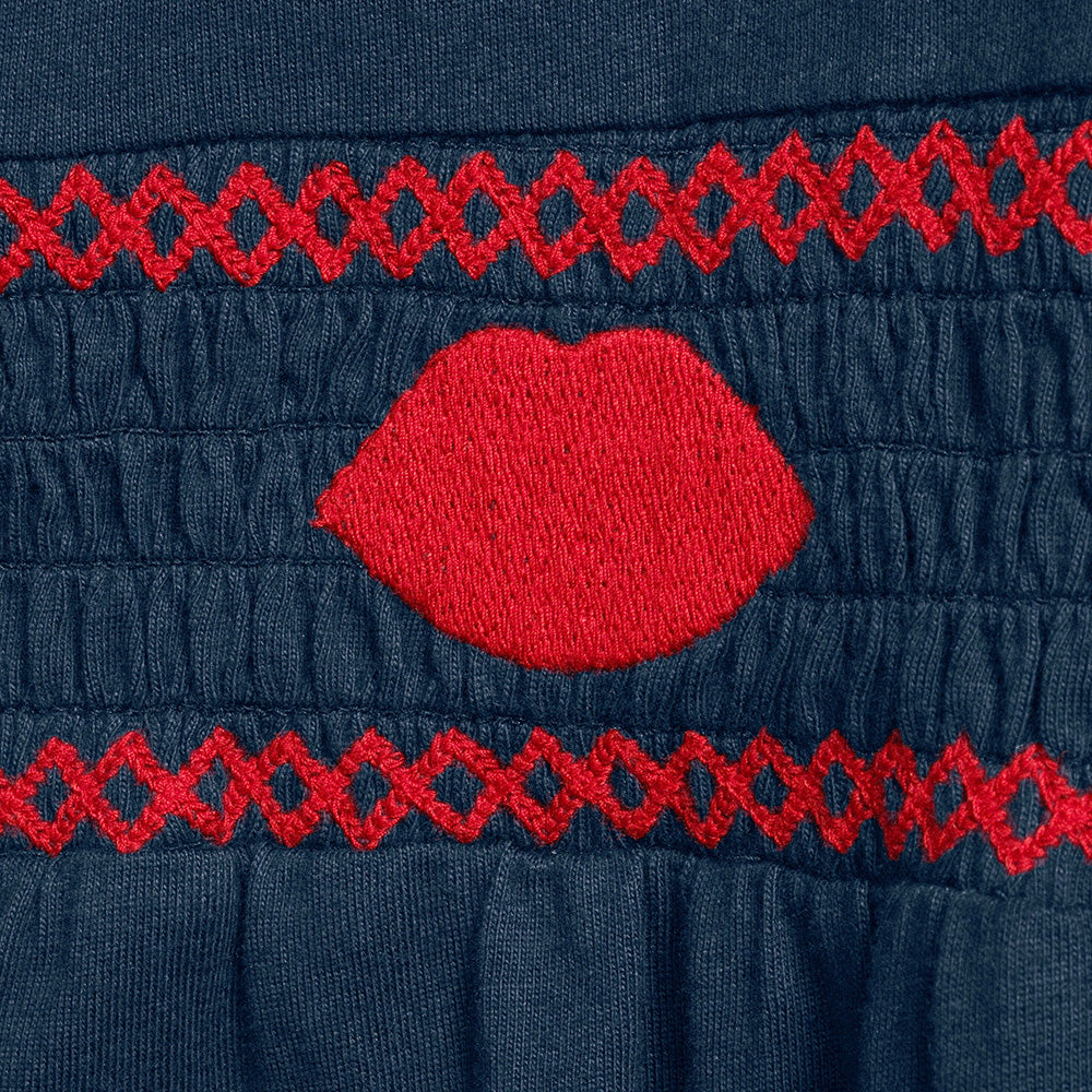 Close up of red embroidered detail on a navy pyjama shirt
