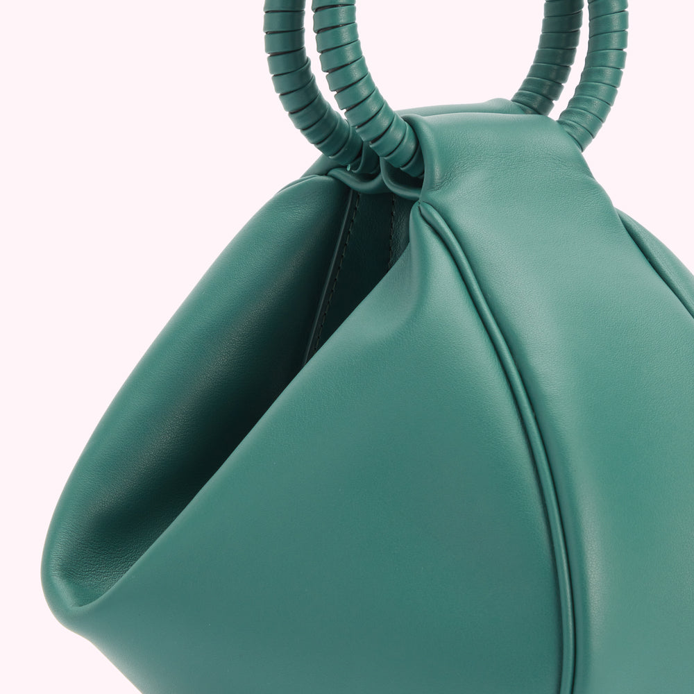 Close-up of a teal leather handbag with unique top handles.
