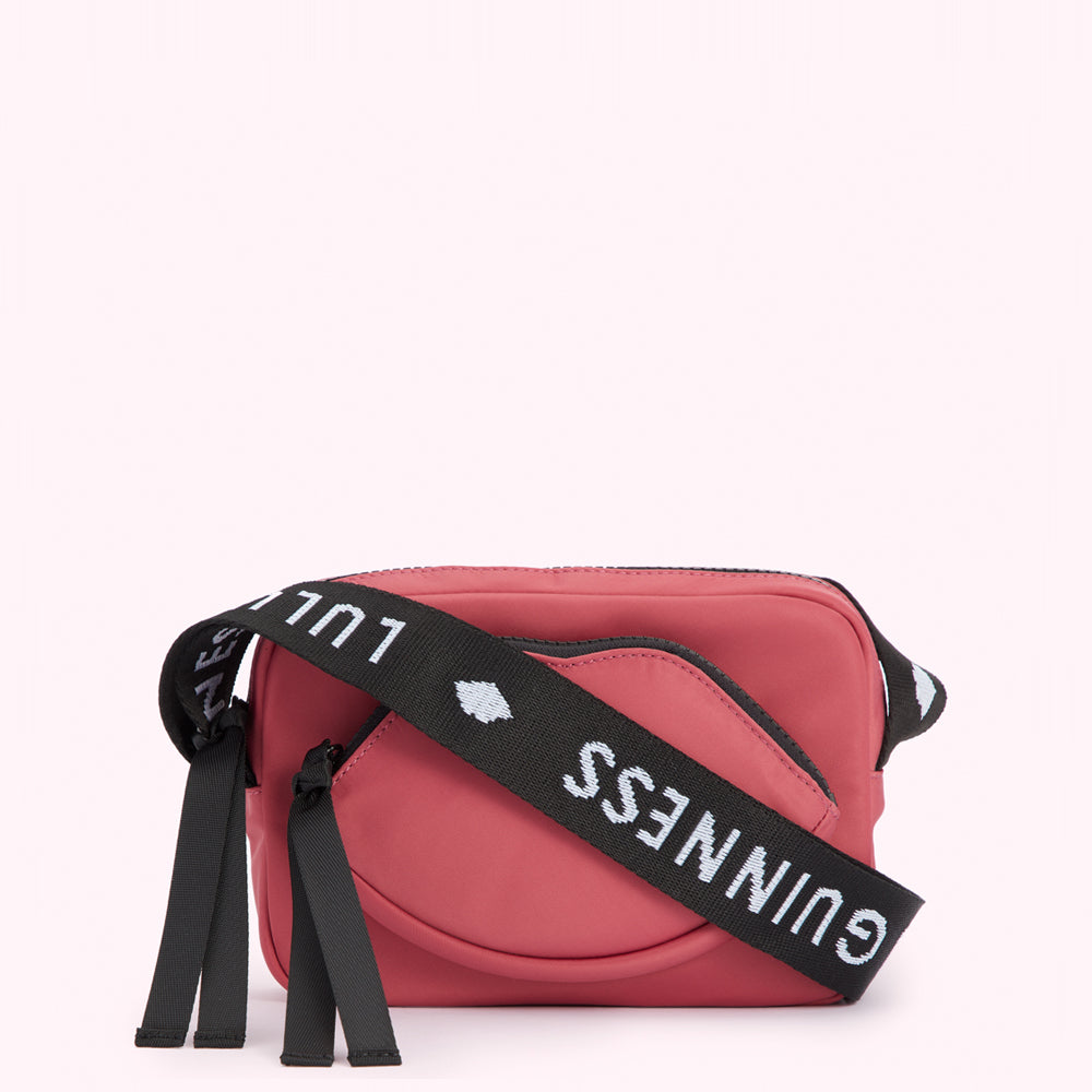 Pink crossbody bag shaped like a lip with a black strap that says "Lulu Guinness" in white.