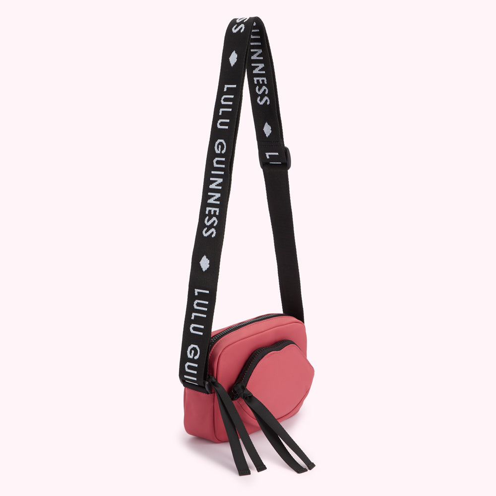 Pink Lulu Guinness lip-shaped crossbody bag with black strap.