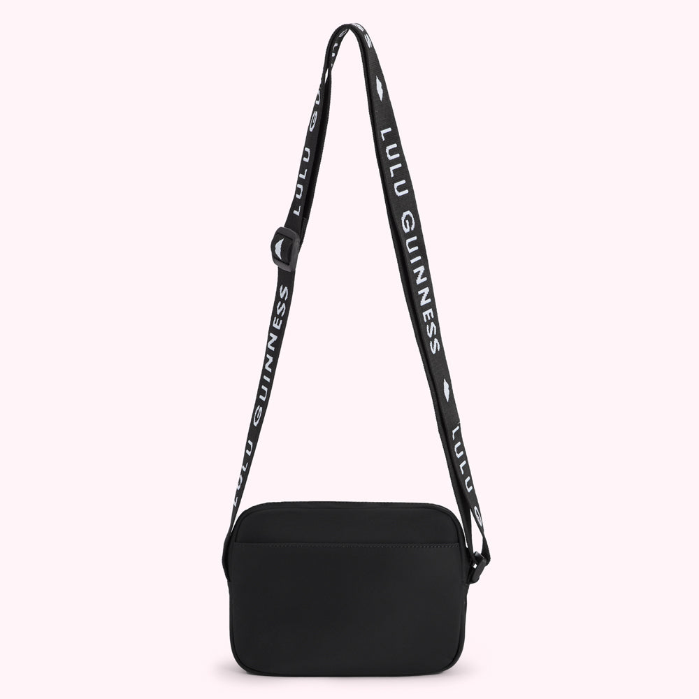 Black Lulu Guinness crossbody bag with adjustable strap featuring the brand's name.
