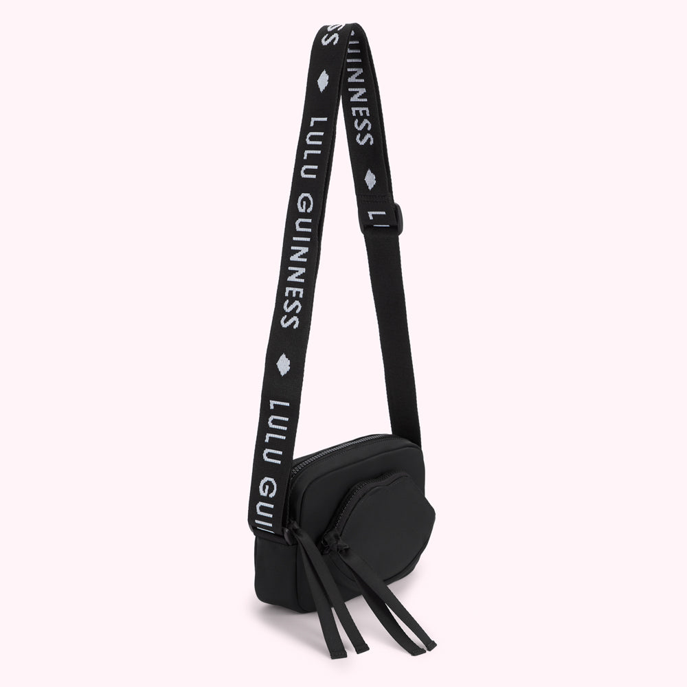 Black crossbody bag with a lip-shaped front detail and a strap featuring the Lulu Guinness logo.
