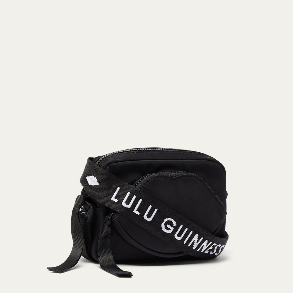 Black bag with 'Lulu Guinness' strap on a light grey background