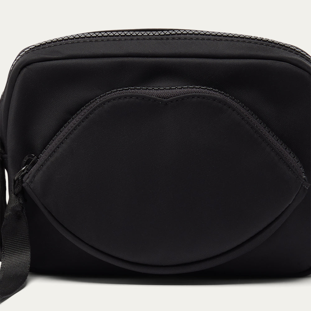 Black crossbody bag with a lip-shaped pocket on a white background