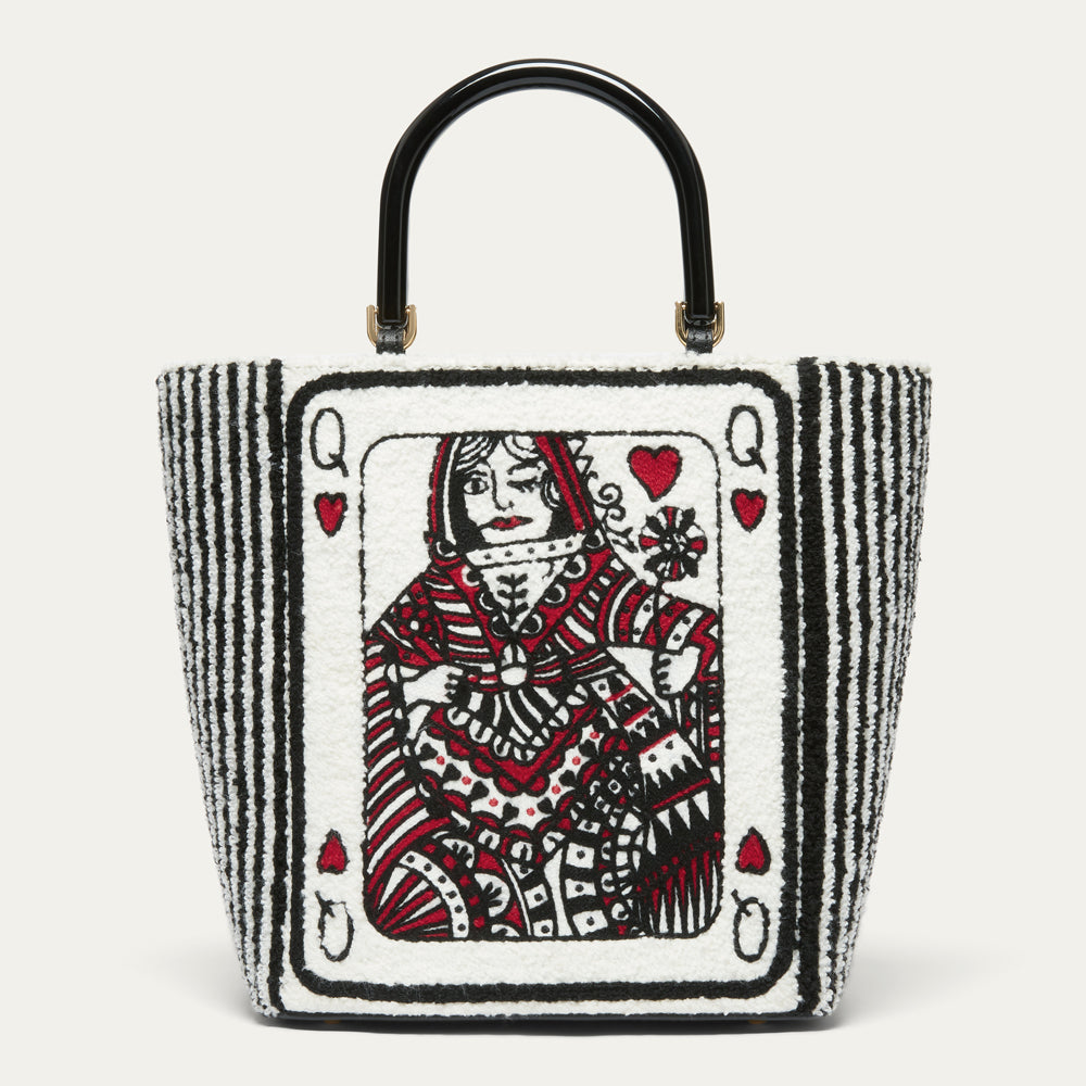 A structured white boucle tote bag with a red and black illustrated queen playing card design on front and back with black stripe side panels and a glossy black top handle.